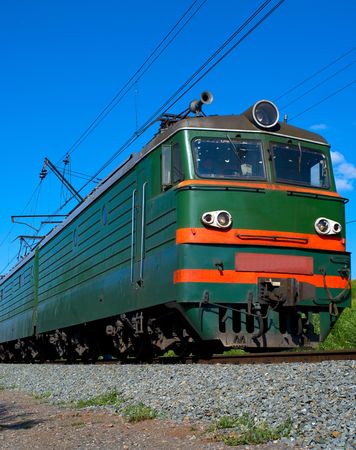 green locomotive going on railway against blue skyの写真素材