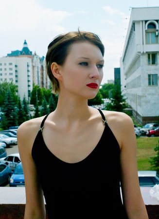 Young serenity girl in black dress against urban landscapeの写真素材