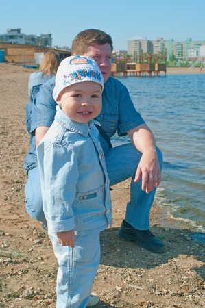 Men with a little boy against summer nature with lake. Shallow DOFの写真素材