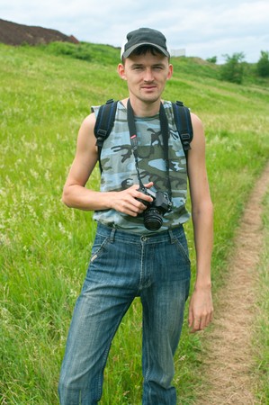 The smiling photographer with camera against summer landscape.の写真素材