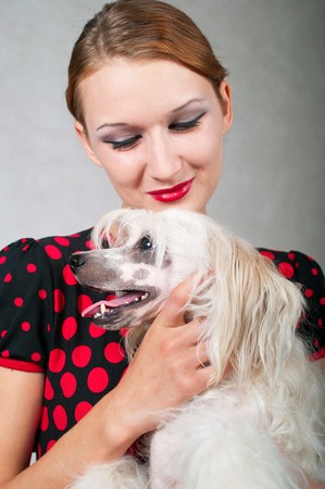 The beautiful girl and chinese crested dog on grey background. Shallow DOF, focus on dog の写真素材