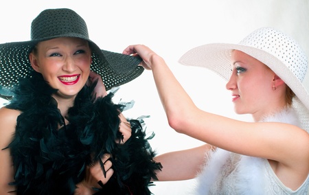 Two beautiful girls in hat and boa on light backgroundの写真素材