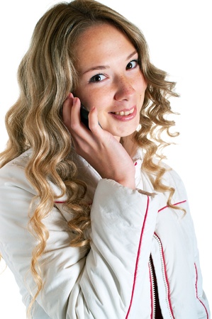 beautiful smiling girl in white jacket with cellular phone on a white background. Isolation の写真素材