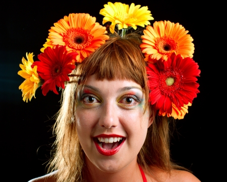 The beautiful girl with a wreath of flowers on her head. On black backgroundの写真素材