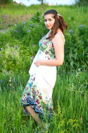 The beautiful young girl in light dress on a the summer green backgroundの写真素材