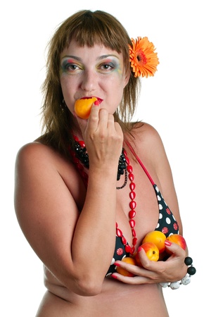The young woman in bathing suit eating apricots. Isolated on white. の写真素材