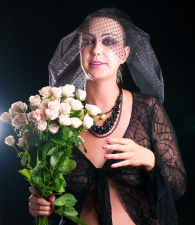 Girl in a black veil with pink roses on black background. Shallow DOF の写真素材