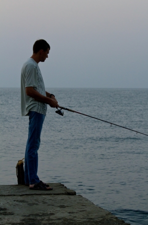 Angler on the sea beach in morning sun. Shallow DOFの写真素材