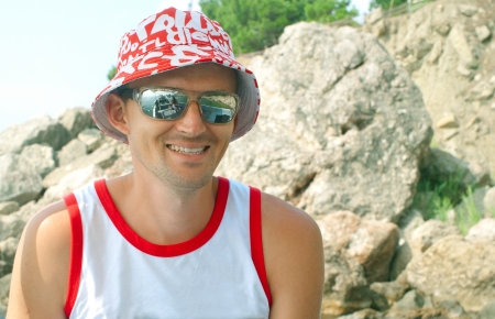 The young men against mountain. Sunglasses reflected the boat and the sea の写真素材