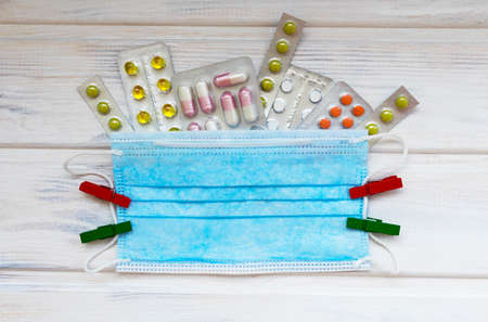 Medical flatlay with mask and tablets on a white wooden background. Medical concept. Top view.