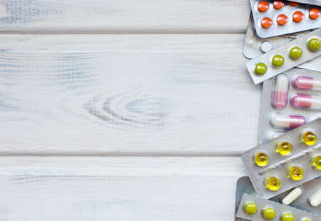 Medical flatlay with mask and tablets on a white wooden background. Medical concept. Top view.