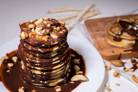 chocolate pancake with bananas, nuts and chocolate sauce. the toning. Wooden board with pancakes on the background.の写真素材