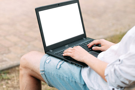 Portrait of a handsome man working with laptop sitting on a bench