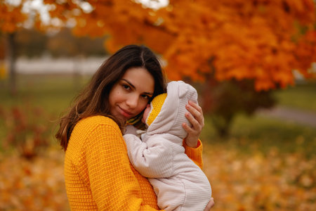 happy family mother and baby laugh with leaves in nature autumn