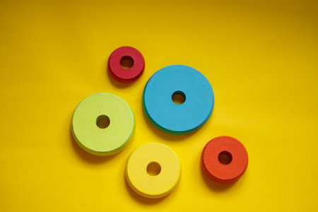 colorful round wooden toy blocks isolated on yellow backgroundの写真素材