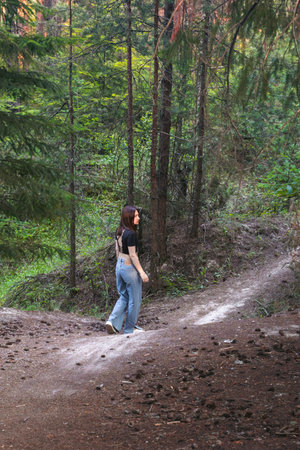 A young woman strolling alone through a lush forest, enjoying solitude and connection with nature....