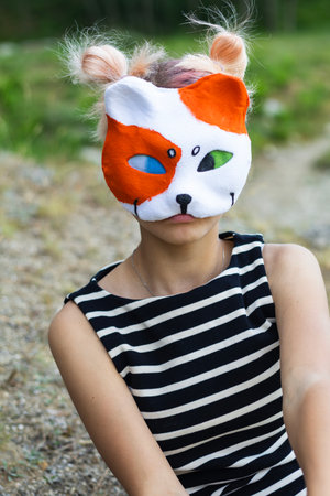 Teen quadrobics girl outdoors, with a handmade cat mask and ear-like buns, mimicking animals.の写真素材