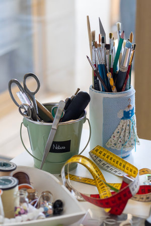 Art & craft supplies: paintbrushes, scissors, tape, sewing notions on a table. Inspire your next...