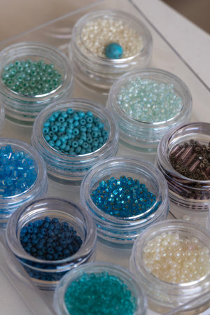 A close-up view of small, colorful seed beads neatly organized in clear plastic containers. Ideal...
