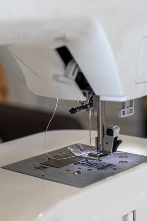 A detailed close-up of a sewing machine, showing the threaded needle, presser foot, and stitch...