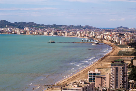 Panoramic Durres, Albania: vibrant city skyline by the Adriatic Sea. Modern buildings line sandy beaches, framed by distant hills and piers.の写真素材