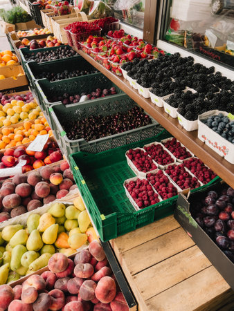 Fresh Seasonal Fruits Displayed at Local Market. Colorful arrangement of various ripe fruits arranged in crates and containers at vibrant farmers market, abundance of summer produce. First-person viewの写真素材