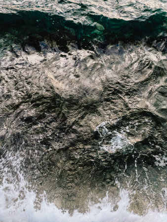 Dark green ocean water displaying white foam and small waves, creating textured natural background...