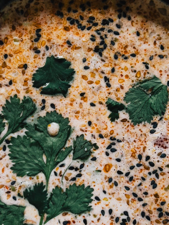 Aromatic Thai soup features creamy broth, fresh cilantro leaves, and sprinkle of black sesame seeds, creating flavorful and visually appealing culinary experience. Savory Thai soup with coconut brothの写真素材