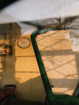 Vintage weighing scale in abandoned shop with clock in background, illuminated by warm sunset light filtering through wire mesh, creating nostalgic atmosphere. Weathered weighing scale, wall clockの写真素材