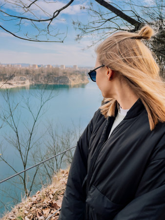 Blonde tourist admiring beautiful turquoise water of Zakrzowek lake surrounded by cliffs and rocks, popular destination for locals and tourists in Krakow, Poland, on sunny spring day. Turquoise lakeの写真素材