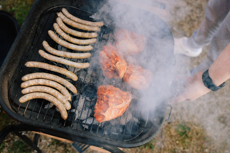 Sizzling chicken and sausages grilling over hot charcoals, smoky flavor rising, professional chef...