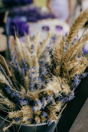 Dried lavender and wheat stalks bundled in rustic metal bucket create charming centerpiece, set...
