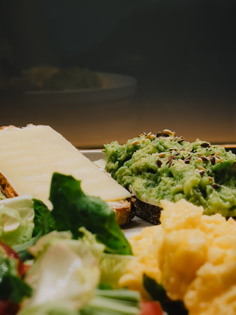 Wholemeal bread toasts with mashed avocado and cheese, scrambled eggs and fresh salad with lettuce, spinach, radish and tomato compose healthy breakfast or brunch. Nutritious morning meal. Good dietの写真素材