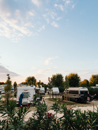 Campers parked in designated spots create tranquil and inviting atmosphere, basking in warm glow of setting sun, perfect for relax and outdoor enjoyment. Camping environment, relaxing outdoor moodの写真素材