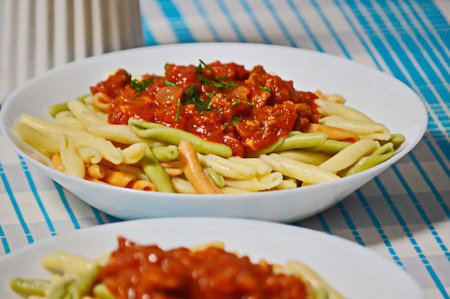 pasta with tomato sauce and parsley on a blue tableclothの写真素材