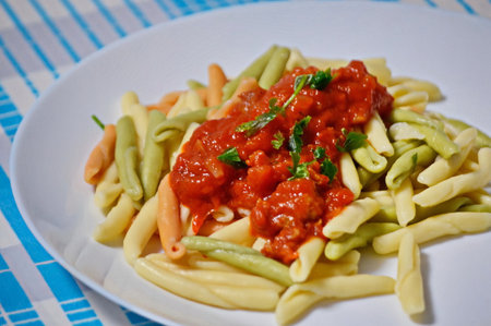Pasta with tomato sauce and green beans on a white plate.の写真素材