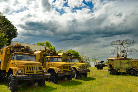 Abandoned military vehicles on a grassy field in front of a cloudy skyの写真素材