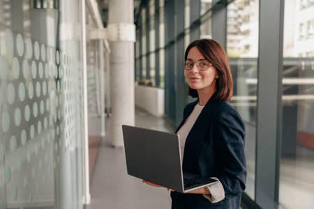 A confident and successful businesswoman is working with a laptop in a modern office environmentの写真素材