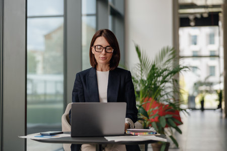 A businesswoman concentrating on her work with a laptop in a greenthemed officeの写真素材