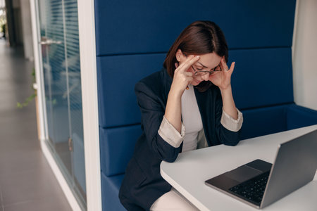 Stressed Businesswoman Concentrating while Working Remotely on Laptop in Modern Officeの写真素材