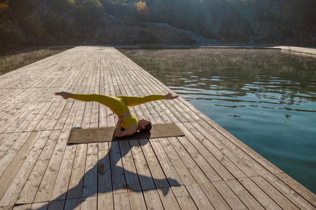 Engaging in a Serene Yoga Practice by the Water while Watching the Sunrise is Refreshingの写真素材