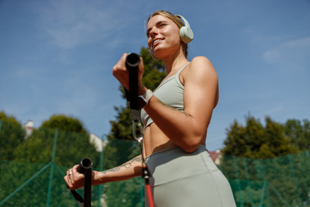 An Active Woman Enjoying Exercising Outdoors While Listening to Music Through Headphonesの写真素材