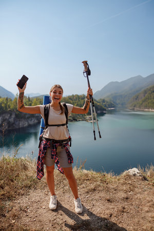 A joyful hiker is celebrating an exciting scenic adventure surrounded by the beauty of natureの写真素材