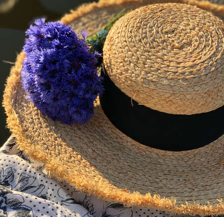 wide-brimmed hat with dark silk ribbon and cornflowers