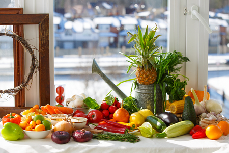 Vegetables and tropical fruits on a table by the windowの写真素材