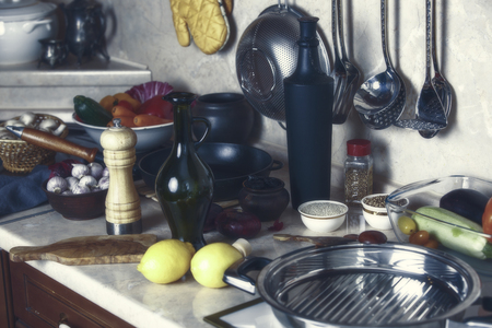 Kitchen table, frying pan, bottles, lemons, onions, spices and vegetables on the kitchen table.の写真素材
