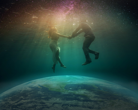 The globe is flooded by the ocean. The starry sky. A young man and a girl hovering under the water.の写真素材