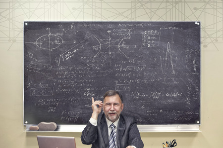 Teacher of mathematics against the background of a board with mathematical examplesの写真素材