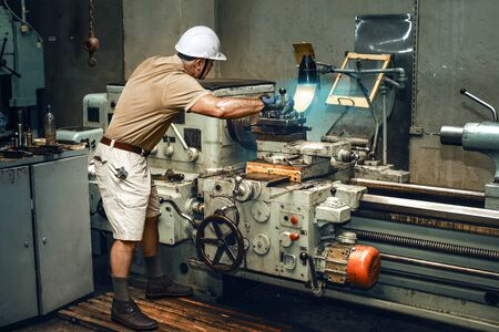 Turner works on an old lathe in a workshop