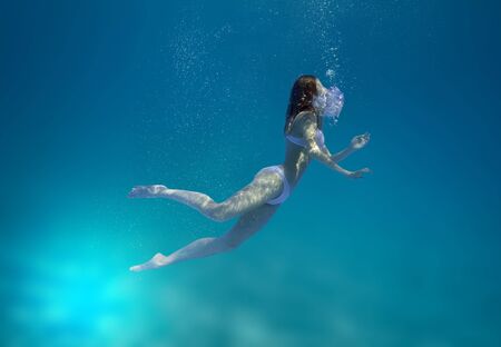 Young guy and girl dive in the tropical sea - imitation of drowningの写真素材